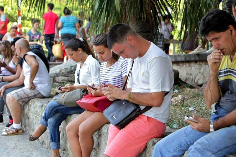 Fotografía del 28 de agosto de 2015 de varias personas revisando el celular durante su coneccion con Wifi, en La Habana, Cuba. Ernesto Mastrascusa EFE