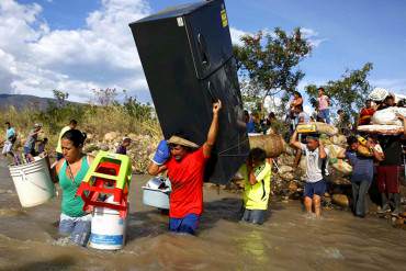 ¡DE IMPACTO! Centenares de colombianos huyen por el río cargando sus enseres en la espalda