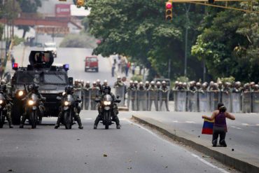 ¡FOTO DEL DÍA! Mujer se arrodilla ante las autoridades en señal de paz y con bandera en mano